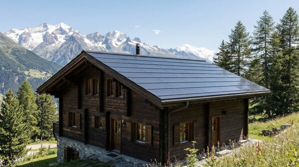 Alpine house with frameless black solar roof modules integrated into pitched roof